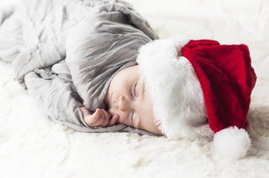 çok güzel, parlak, mutlu bebek beyaz ekose üzerine gri kumaş sarılı beyaz bir battaniye uyku Santa hat