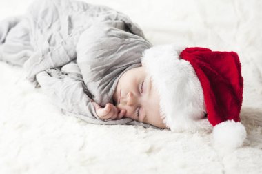 çok güzel, parlak, mutlu bebek beyaz ekose üzerine gri kumaş sarılı beyaz bir battaniye uyku Santa hat
