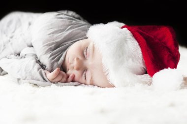 çok güzel, parlak, mutlu bebek beyaz ekose üzerine gri kumaş sarılı beyaz bir battaniye uyku Santa hat