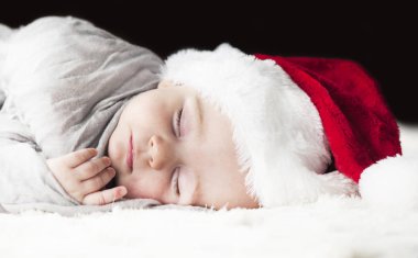 çok güzel, parlak, mutlu bebek beyaz ekose üzerine gri kumaş sarılı beyaz bir battaniye uyku Santa hat