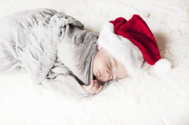 çok güzel, parlak, mutlu bebek beyaz ekose üzerine gri kumaş sarılı beyaz bir battaniye uyku Santa hat