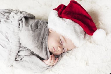 çok güzel, parlak, mutlu bebek beyaz ekose üzerine gri kumaş sarılı beyaz bir battaniye uyku Santa hat