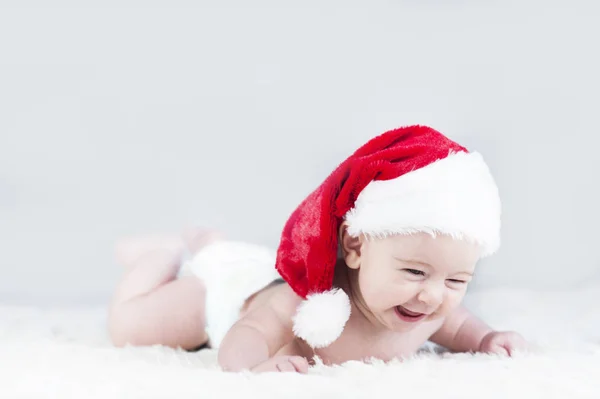 Mycket vackra ljusa känslomässiga glada lilla bebis i Santa hatt kryper — Stockfoto