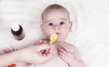Çok küçük bir çocuk, doktorun ofisinde bir bebek ve o öksürük ve bir kaşık alerji için bir ilaç verilir.