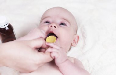 Çok küçük bir çocuk, doktorun ofisinde bir bebek ve o öksürük ve bir kaşık alerji için bir ilaç verilir.