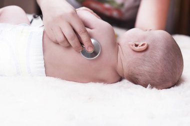 Çok küçük bir çocuk, Bebek, geri doktor ofisinde oturuyor ve Doktor akciğerler, kalp dinler.