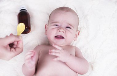 Çok küçük bir çocuk, doktorun ofisinde bir bebek ve o öksürük ve bir kaşık alerji için bir ilaç verilir.