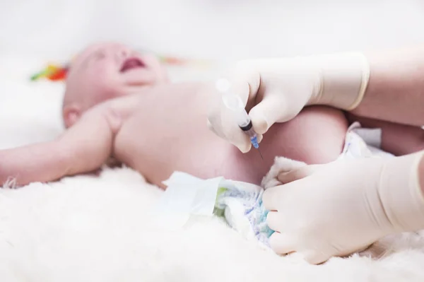 Un niño muy pequeño, un bebé, está acostado en el consultorio del médico y el médico le inyecta . —  Fotos de Stock