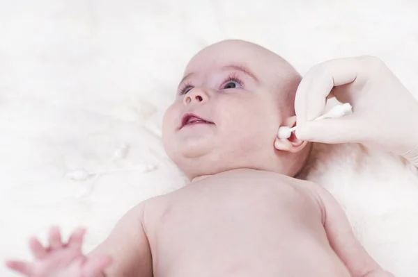 A criança no consultório médico e seus ouvidos são limpos com um cotonete . — Fotografia de Stock
