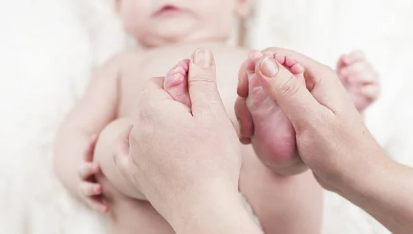 母亲为快乐的宝宝做按摩 在脚上涂油 背景是白色 — 图库照片