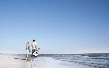 deniz kıyısı gitarda aşık genç bir çift. Romantizm, dönüş