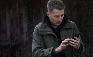 Genç adam gri arka plan üzerinde izole portresi, sergilenen bu onun akıllı telefon, medya içeriği Web'den tarafından etkilendim heyecanlı arıyorum