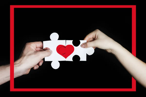 레드 프레임에 사랑 하는 커플의 손에 붉은 마음으로 퍼즐. 발렌타인 데이 개념입니다. 검은 배경에 — 스톡 사진