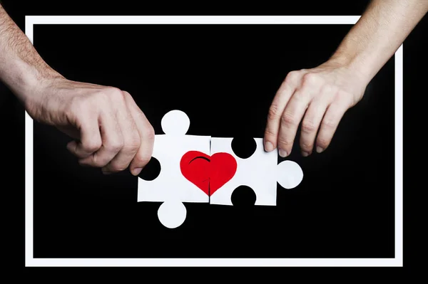 화이트 프레임에 사랑 하는 커플의 손에 붉은 마음으로 퍼즐. 발렌타인 데이 개념입니다. 검은 배경에 — 스톡 사진