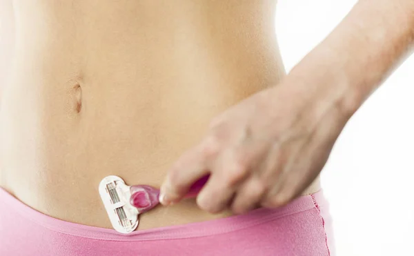 Genç bir kız bir bikini beyaz bir arka plan üzerinde tıraş oluyor. Nazik, sıkılır cilt tahriş etmeden.