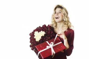 Genç güzel kız beyaz fiyonk ve çiçeklerle onun elinde kırmızı bir hediye ile izole beyaz arka plan üzerinde sevinmektedir. Sevgililer günü kavramı. Sevgililer günü.