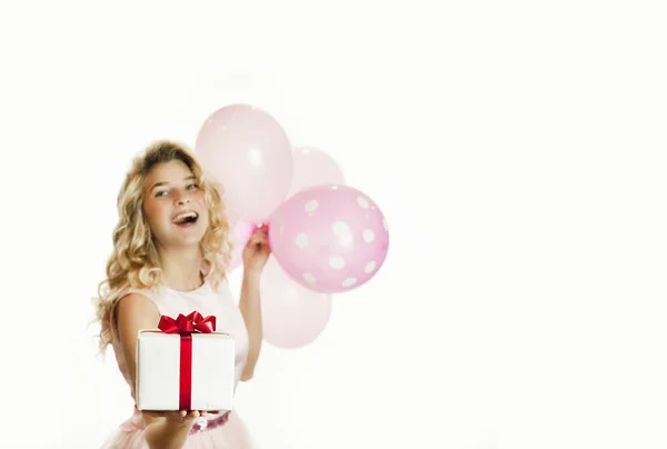 Joven chica hermosa con un regalo blanco con un lazo rojo y bolas en las manos se regocija sobre un fondo blanco aislado. Concepto de San Valentín . — Foto de Stock