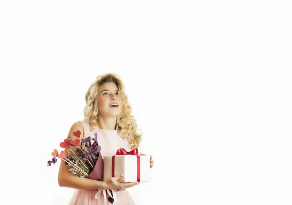 Menina bonita nova com um presente branco com um arco vermelho, flores e bolas em suas mãos se alegra com um fundo branco isolado. Conceito de dia dos namorados . — Fotografia de Stock