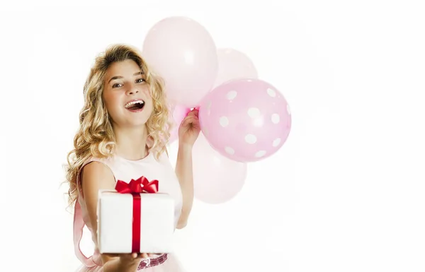 Joven chica hermosa con un regalo blanco con un lazo rojo y bolas en las manos se regocija sobre un fondo blanco aislado. Concepto de San Valentín . Imagen de archivo