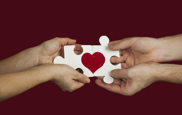 Головоломка с красным сердцем в руках любящей пары. День святого Валентина Концепт. На красном изолированном фоне
