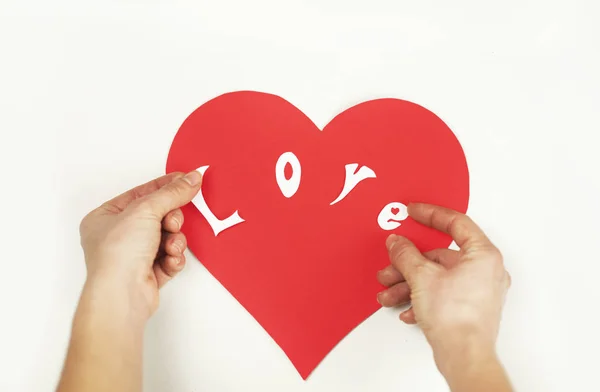 Puzzle with a red heart in the hands of a loving couple. Valentine\'s day concept. On a white background isolated. Love in the shape of a heart