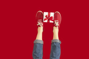 ayakları ile tatil günlerinde bir izole kırmızı arka plan, bir hediye ile bir kız için bir hediye hediyeler, indirimler vererek. Sevgililer günü.