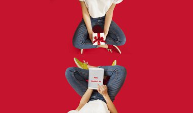 kız bir kırmızı yay ile beyaz hediye ile bir izole kırmızı backgroundvalentines gün üzerinde oturuyor.