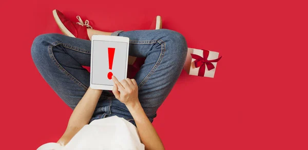 Girl with ipad in her hands, gifts, discounts, sitting on an isolated red background,Valentines Day. — Stock Photo, Image