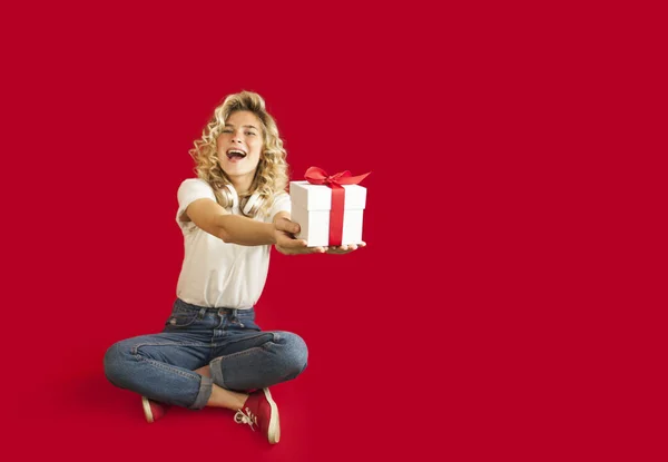 Beautiful girl with a white gift in her hands on a red isolated background in full growth.Valentine's Day concept — Stock Photo, Image