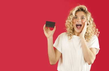 Genç kız izole kırmızı zemin üzerine elinde alımlarda indirim indirim kartı ile tatilde. Sevgililer günü, Sevgililer günü,