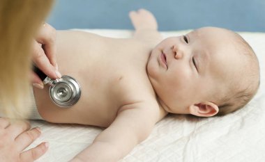 Çok küçük bir çocuk, çocuk, doktor ofisinde yatıyor ve Doktor akciğerler, kalp dinler. Çocuk Sağlığı kavramı