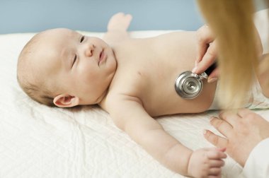 Çok küçük bir çocuk, çocuk, doktor ofisinde yatıyor ve Doktor akciğerler, kalp dinler. Çocuk Sağlığı kavramı