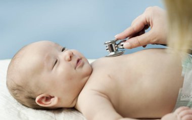 Çok küçük bir çocuk, çocuk, doktor ofisinde yatıyor ve Doktor akciğerler, kalp dinler. Çocuk Sağlığı kavramı