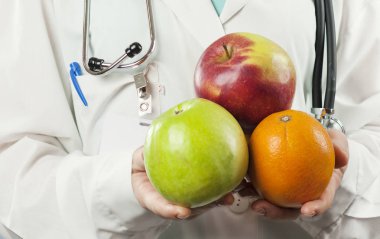 güzel kız doktor beslenme uzmanı izole mavi zemin üzerine elinde meyve ile. Sağlıklı beslenme kavramı