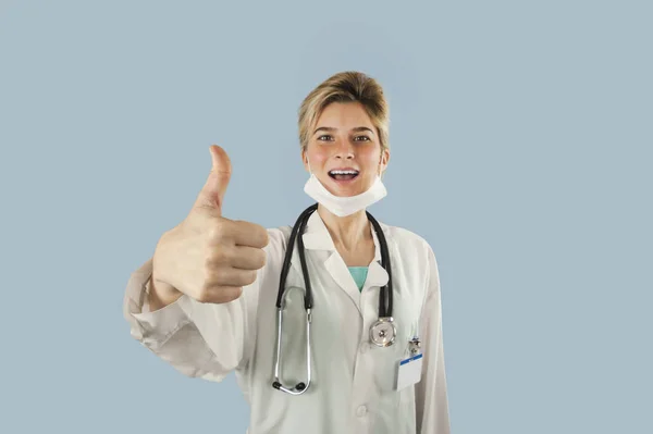 年轻的医生女孩在蓝色被隔绝的背景显示拇指 概念医学与健康 — 图库照片