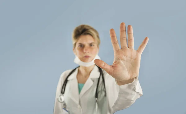 年轻的女孩医生显示与手手掌停止标志在蓝色被隔绝的背景 概念医学与健康 — 图库照片