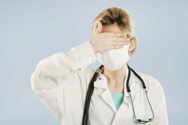 年轻的医生女孩闭上眼睛 用一只手在蓝色被隔绝的背景 概念医学与健康 — 图库照片