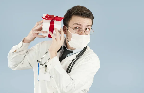 genç doktor öğrenci bir izole mavi background.concept ilaç ve sağlık, tatil ve hediyeler onun elinde bir hediye ile