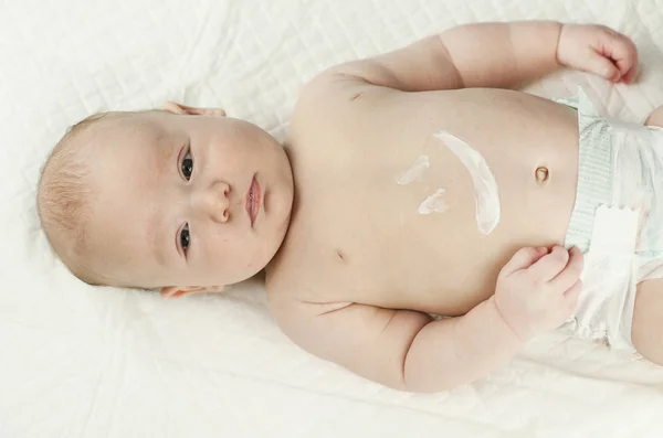 用奶油画的婴儿肚子上的微笑标志 婴儿躺在白色的床单在医生的办公室 — 图库照片