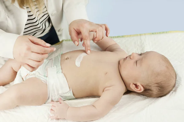 Smile sign on baby tummy drawn with cream. baby lying on white sheets at the doctor's office