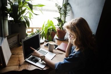 Bir kız bir dizüstü bilgisayar ile bir kafede kahve, alır zevk ile rahat bir yerde çalışıyor. Freelancing kavramı