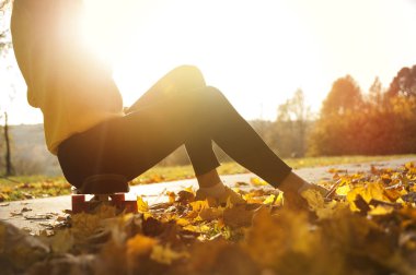 genç bir kızın bacak hareketi günbatımı bir kaykay üzerinde yolda için. Spor ve geliştirme kavramı