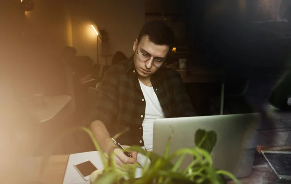 A guy in a cafe with a laptop working in a cozy place with a cup