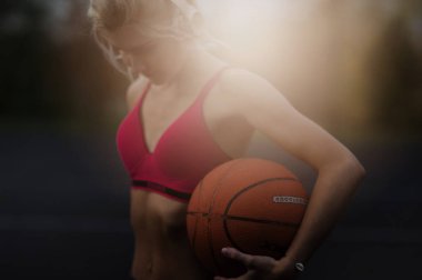 Kulaklıkla basketbol oynarken poz veren muhteşem, konsantre olmuş güzel ve güçlü bir kadının portresi. Sağlıklı yaşam tarzı konsepti, sportif kız.