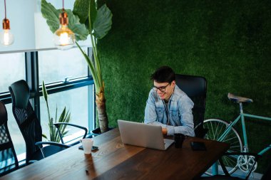 Genç programcı modern ofiste dizüstü bilgisayar üzerinde çalışan yeni işinde