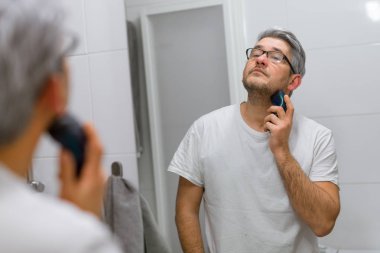 Elektrikli tıraş makinesi ile gri saçlı adam tıraş sakal portresi