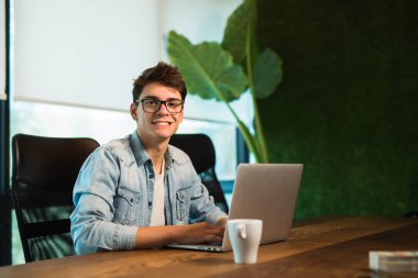 Web tasarımcısı modern ofiste dizüstü bilgisayar üzerinde çalışıyor