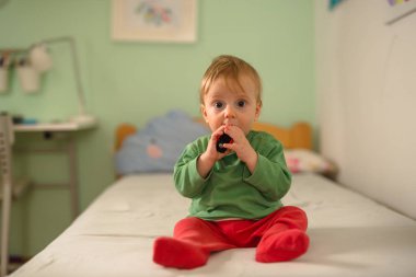 küçük çocuk yatakta oturan ve oyuncak ile oynarken