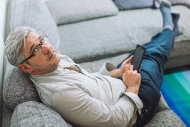 Adam evde tablet kullanarak kanepede rahat