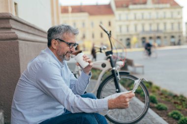 Olgun adam şehirde gazete açık okuma kahve içme zaman zevk